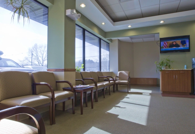 Modern dental waiting room with comfortable seating, large windows, and contemporary decor.