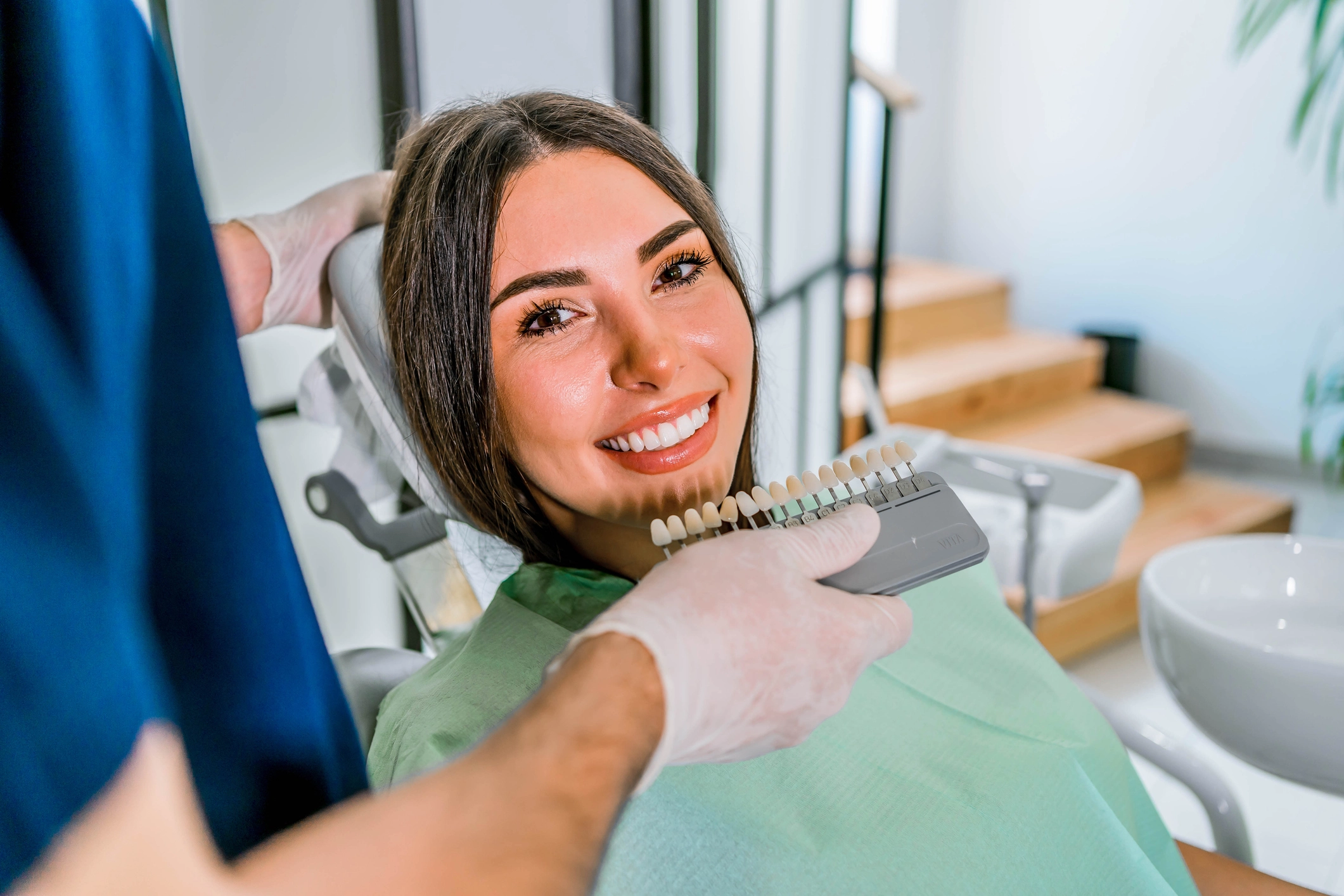 Smiling female patient receiving dental examination in modern dental office setting.