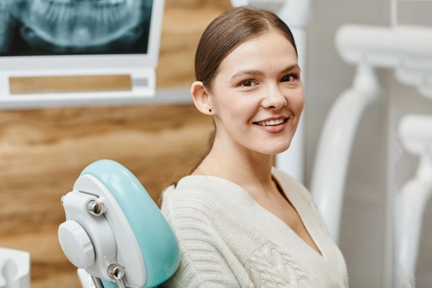 Woman holding dental model smiling in modern dentistry office with equipment visible.